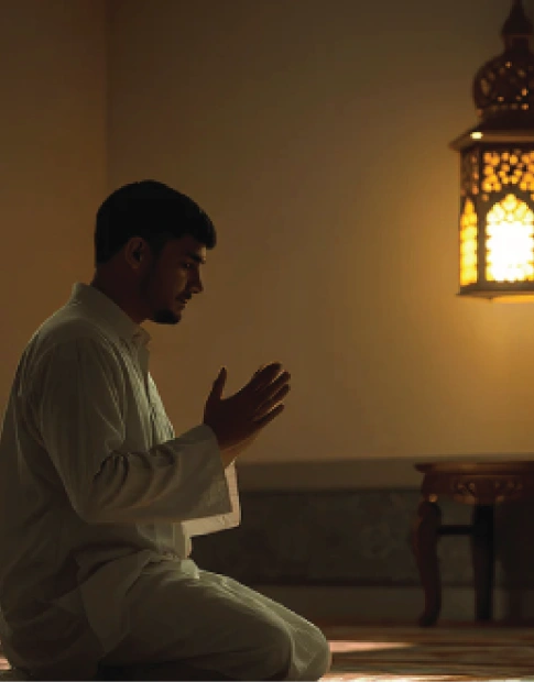 Young Muslim man sitting in prayer and making dua with warm lantern light